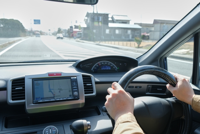 高速道路を運転する車のハンドルを握る手